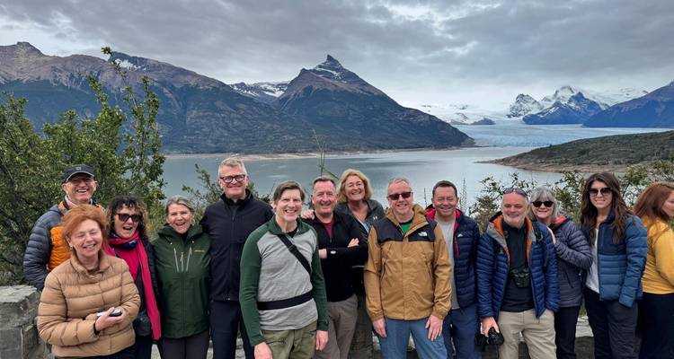 El grupo de turistas posa con un telón de fondo de un lago alimentado por glaciares y las montañas patagónicas