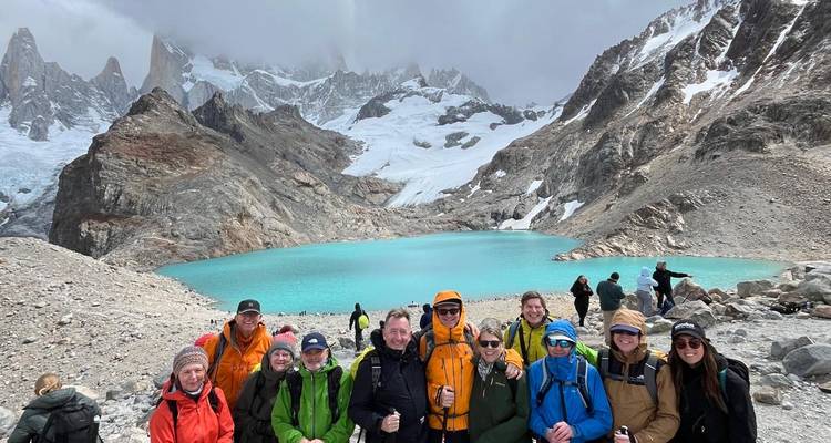 Trekkers felices frente a una laguna de un turquesa vibrante bajo el Monte Fitz Roy y picos nevados