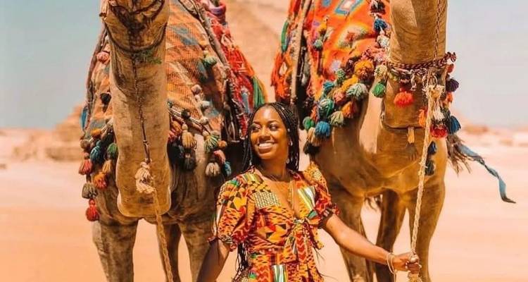 Vrouw poseert met kamelen getooid in kleurrijke stoffen in Egypte.