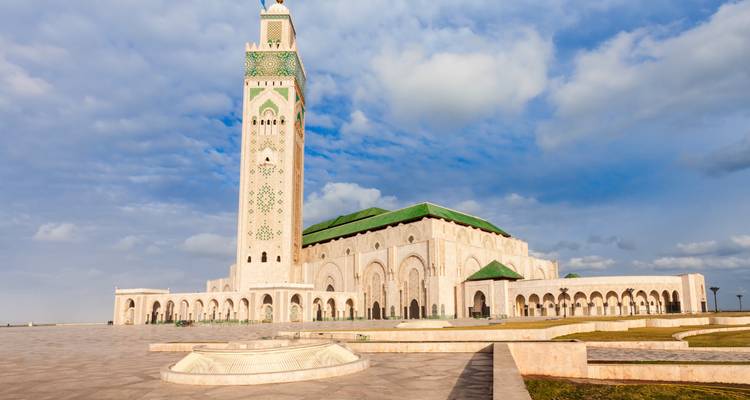 Weite Platzansicht der Hassan-II-Moschee von Casablanca und des Minaretts unter fleckigen Wolken.