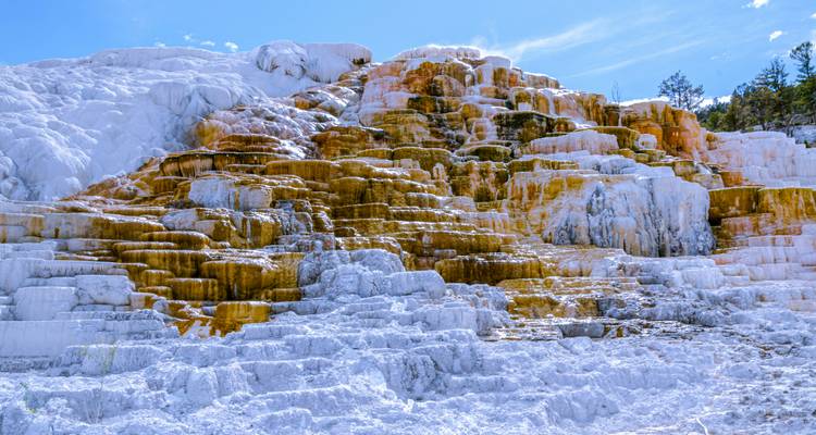 Terraced hot springs with vibrant rock colors and clear skies.
