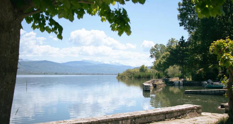 Een serene meer met bergen en groen die weerspiegelen op het water.