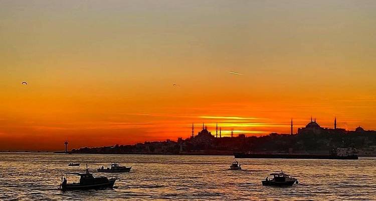 Een levendige zonsondergang boven de stadshorizon en zee.