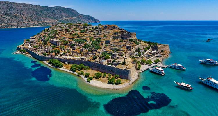 Luchtfoto van het eiland Spinalonga op Kreta, omringd door blauw water.