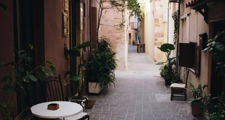 Smalle steeg met planten en tafels, die een gezellige sfeer creëert.