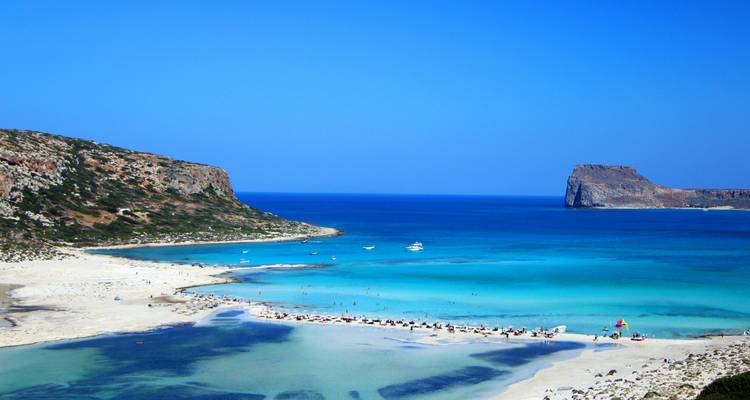 Lagon turquoise et plage de sable blanc à Balos avec bateaux et caps rocheux