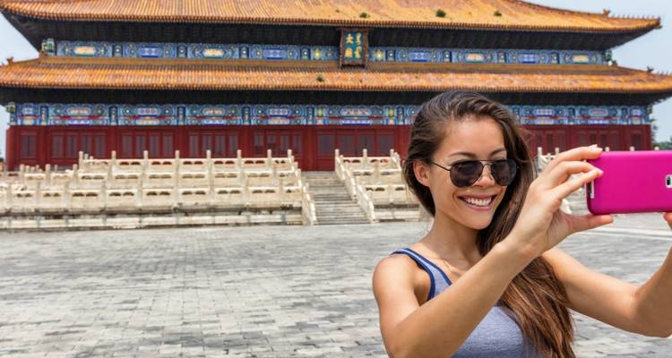 Vrouw die een selfie neemt voor een traditioneel Chinees gebouw.