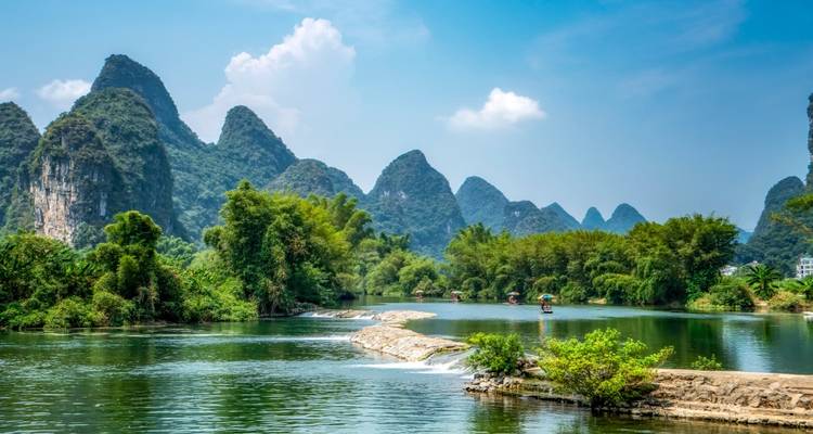 Rivier met weelderige groene karstheuvels op de achtergrond.