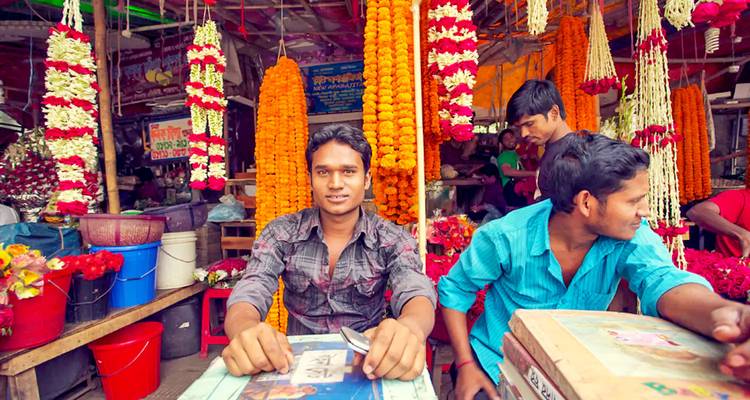 Mannen die bloemenslingers verkopen op een levendige markt.