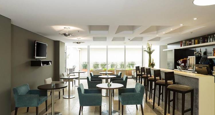 Zeitgenössischer Bar- und Speisebereich in einem Hotel mit Tischen und einer Theke.