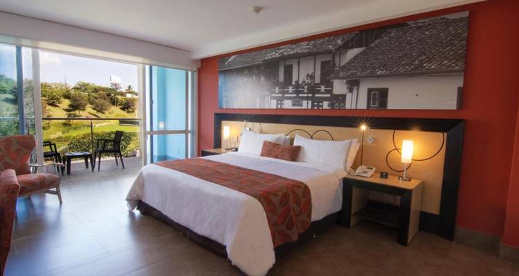 Hotelzimmer-Interieur mit einem Bett, Wandkunst und Balkonblick.