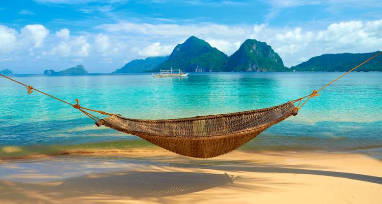 Scène paisible d'un hamac sur une plage tropicale avec des vues magnifiques sur l'île.