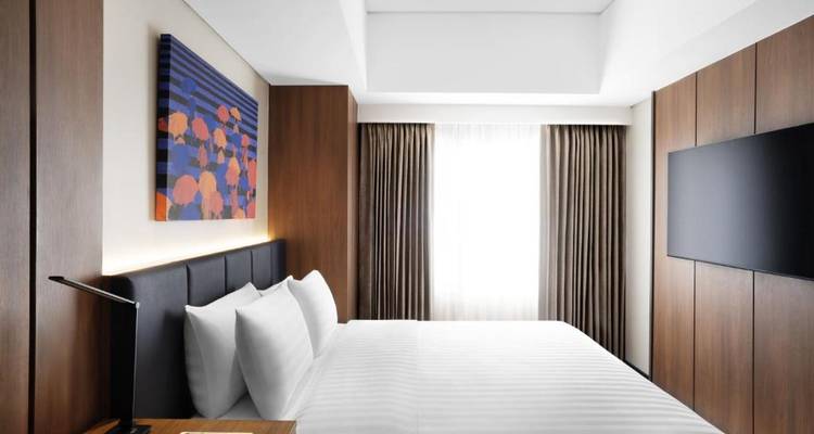 Einfaches und modernes Hotelzimmer mit weißer Bettwäsche und Holzelementen.