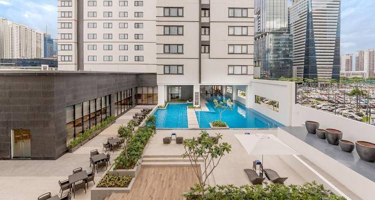 Moderner Außenpoolbereich mit Stadtpanorama im Hintergrund.