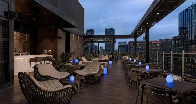 Elegante Dachterrassen-Lounge mit Stadtblick und Ambientebeleuchtung.