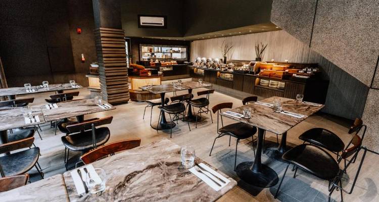 Elegante Innenrestaurant-Atmosphäre mit dunklen Tönen und einem Buffet im Hintergrund.