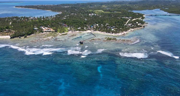 Vue aérienne d'une île entourée d'eau bleue claire et d'une végétation luxuriante.