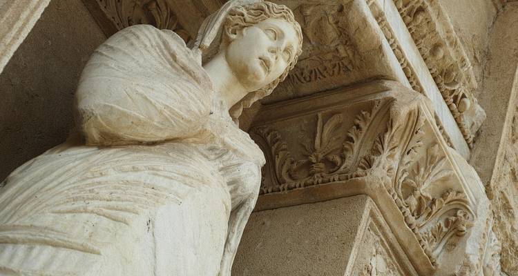 Gros plan d'une statue de pierre classique avec des sculptures complexes.