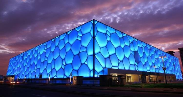 Le Cube d'Eau illuminé de lumières bleues pendant le crépuscule.