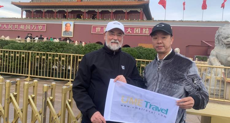 Deux hommes posant avec une bannière de compagnie de voyage sur une place publique.