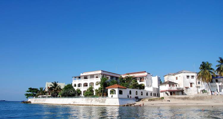Villa blanche en bord de mer avec un ciel bleu clair et l'océan.