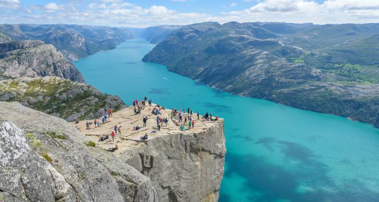 Dutzende von Wanderern stehen auf der Preikestolen-Klippe und blicken auf den türkisfarbenen Lysefjord weit unten.