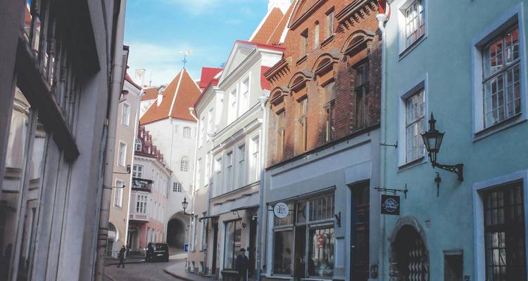 Een smalle geplaveide straat in Tallinn met kleurrijke gebouwen.
