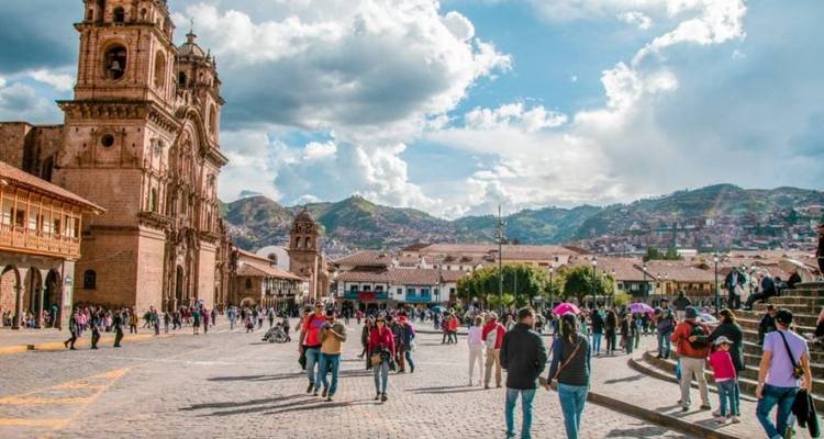 Place animée à Cusco avec des gens et des bâtiments historiques.