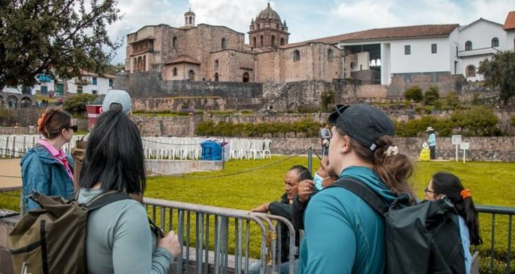 Groupe de personnes écoutant un guide près d'une vieille église à Cusco.
