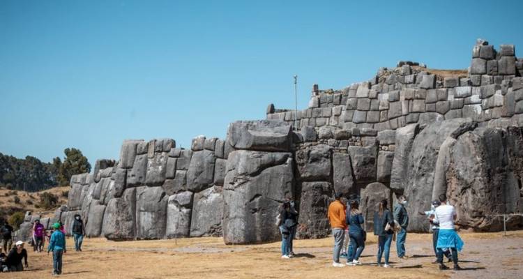 Des personnes explorant des ruines antiques avec de grands murs de pierre.