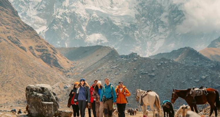 Un groupe de randonneurs dans un paysage montagneux avec des chevaux au pâturage.