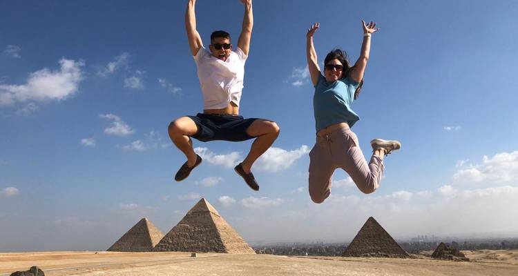 Deux personnes sautant devant les pyramides de Gizeh.