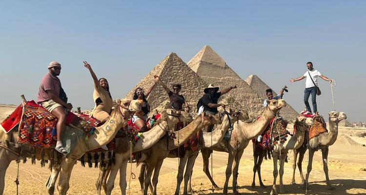 Groupe de personnes montant des chameaux devant les Pyramides.