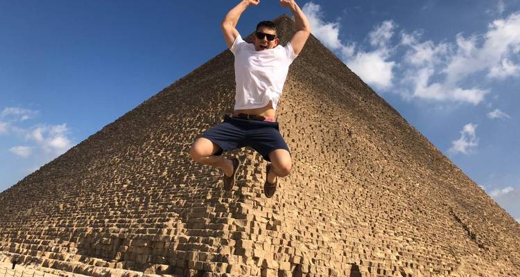 Homme sautant devant une grande pyramide.