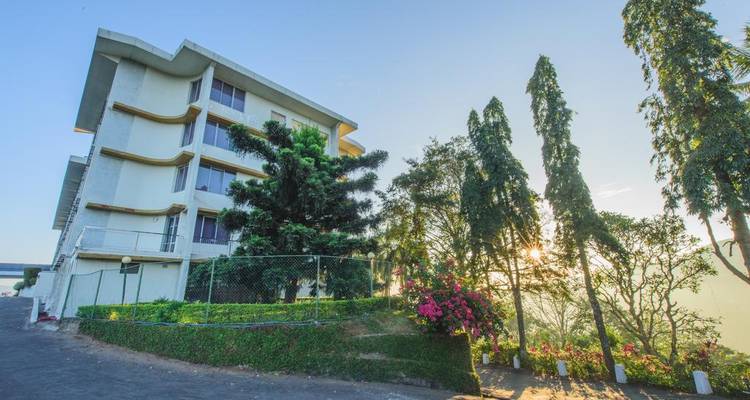 Außenansicht eines modernen Hotelgebäudes mit Bäumen und klarem blauem Himmel.