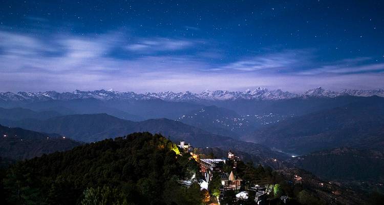 Panorama nocturne d'une région montagneuse sous un ciel étoilé.
