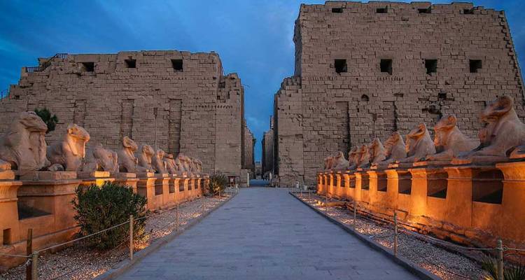 Avenue de sphinx la nuit menant aux ruines d'un temple.
