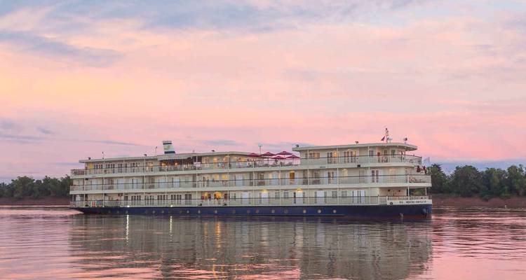 Un grand navire de croisière sur une rivière au coucher du soleil.