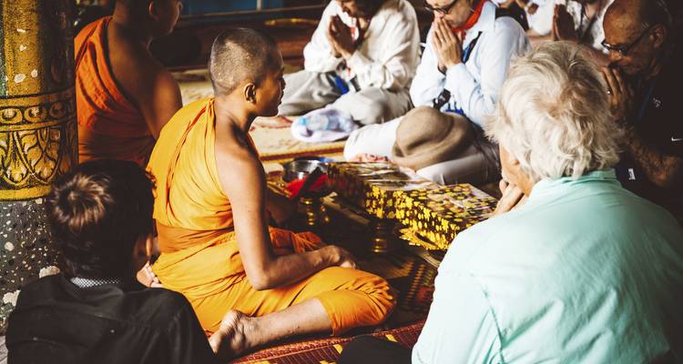 Moines et touristes participant à une cérémonie traditionnelle dans un temple.