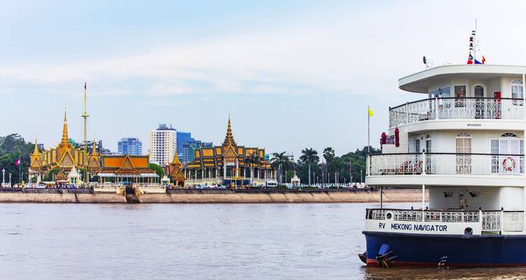 Scène de rivière avec un bateau de croisière et un paysage urbain en arrière-plan.