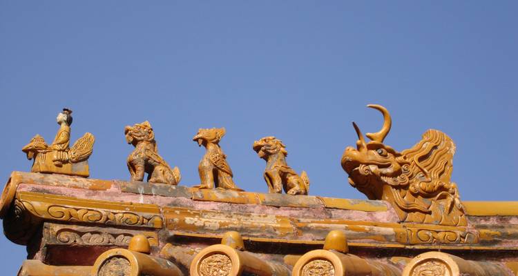 Figuras ornamentales sobre un tejado contra un cielo despejado.