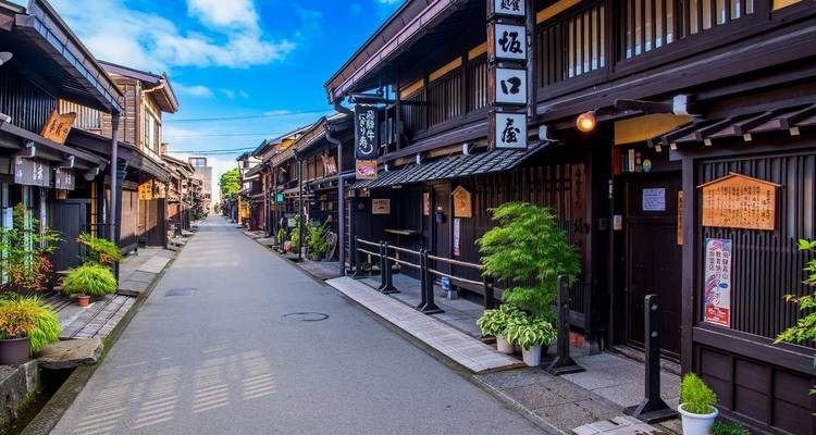 Calle japonesa tradicional con edificios de madera bajo cielo azul.