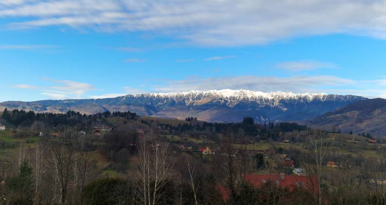 Montagnes enneigées dans un paysage pittoresque, avec de petites maisons au premier plan.
