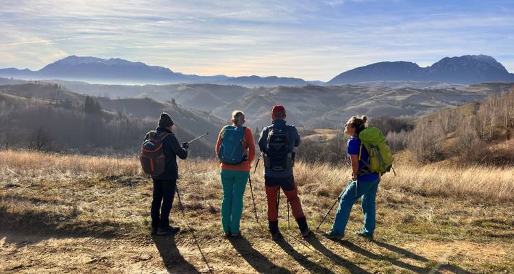 Des randonneurs debout sur une colline surplombant des montagnes au loin.