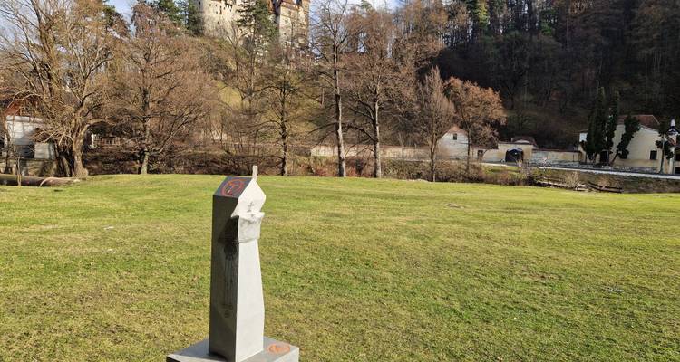 Zone rurale avec une borne en pierre au premier plan et des arbres alentour.
