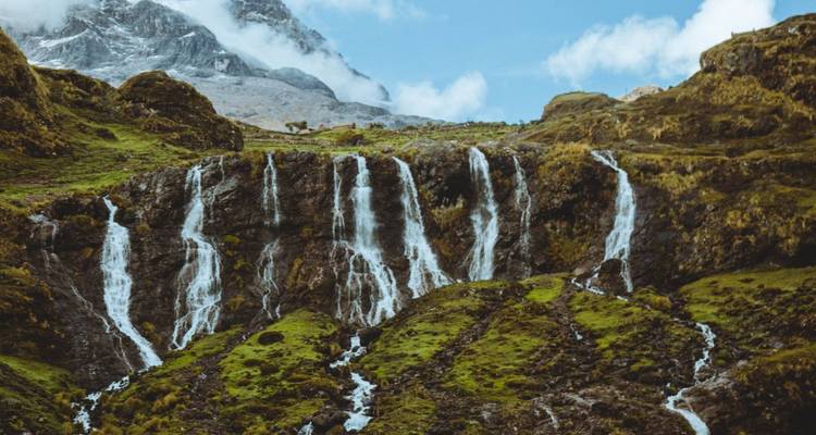 Vista panorámica de cascadas en cascada contra terreno montañoso.