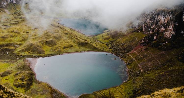 Vista aérea de dos lagos entre montañas y cielos nublados.