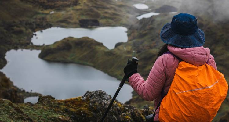 Excursionista con mochila contemplando una vista escénica de montaña y lago.