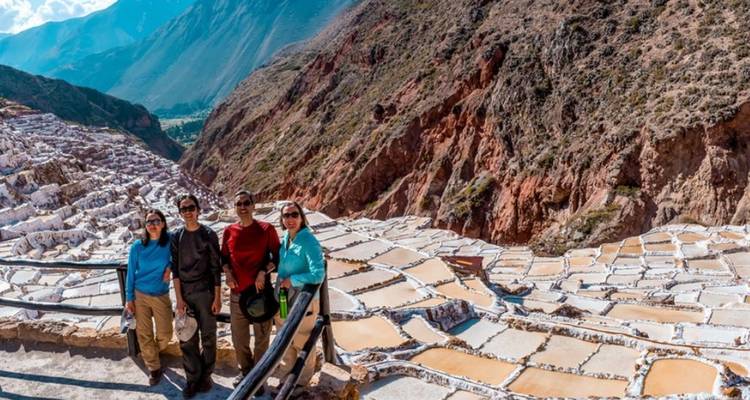 Grupo de cuatro personas posando frente a estanques de evaporación de sal en terrazas.