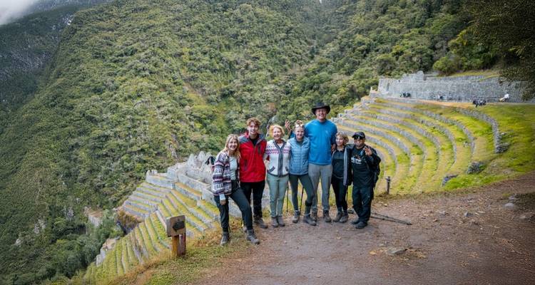 Group of hikers posing in front of ancient terraced ruins.